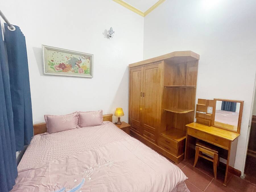 Un dormitorio con una cama, un armario de madera, un escritorio con espejo y un reloj de pared.