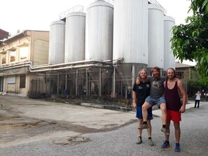 A group of people standing in front of industrial buildings with large cylindrical silos. - Nam My Van Homestay (Thai Nguyen)