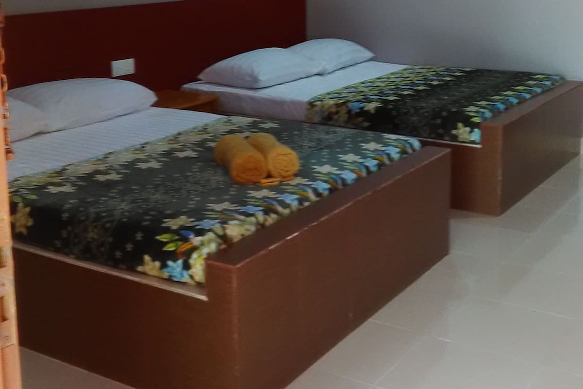 A hotel room with two beds, a red headboard, and an air conditioning unit on the wall.