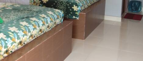 A room with two beds, a ceiling air conditioner, and a tiled floor.