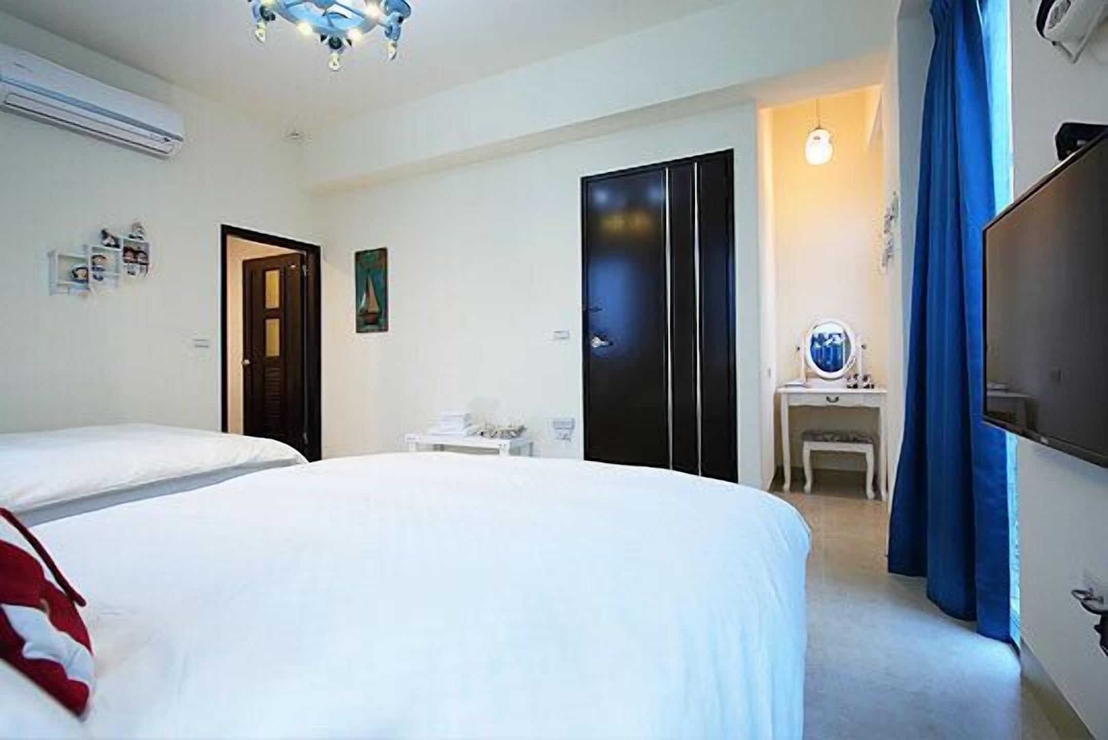 Una habitación de hotel con cama, escritorio, silla, televisor y armario.