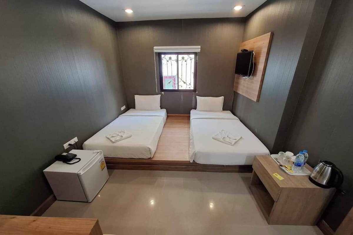 A hotel room with two beds, a small table, a desk, a TV, and a window with a view.