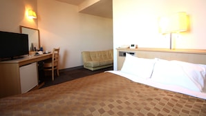 A hotel room with a bed, a desk with a television, a chair, a sofa, and a lamp. - Hotel LC Gifu-Hashima (Hashima)