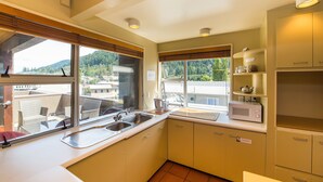 A kitchen with a sink, microwave, and cabinets. - Tahuna Pod Hostel (Queenstown)