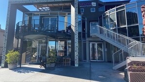 A modern hostel with a glass facade, outdoor seating, and a staircase leading to the upper level. - Tahuna Pod Hostel (Queenstown)