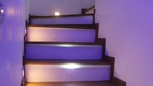 Un escalier avec des marches en bois et une rampe, éclairé par un système d’éclairage dissimulé sous les marches.