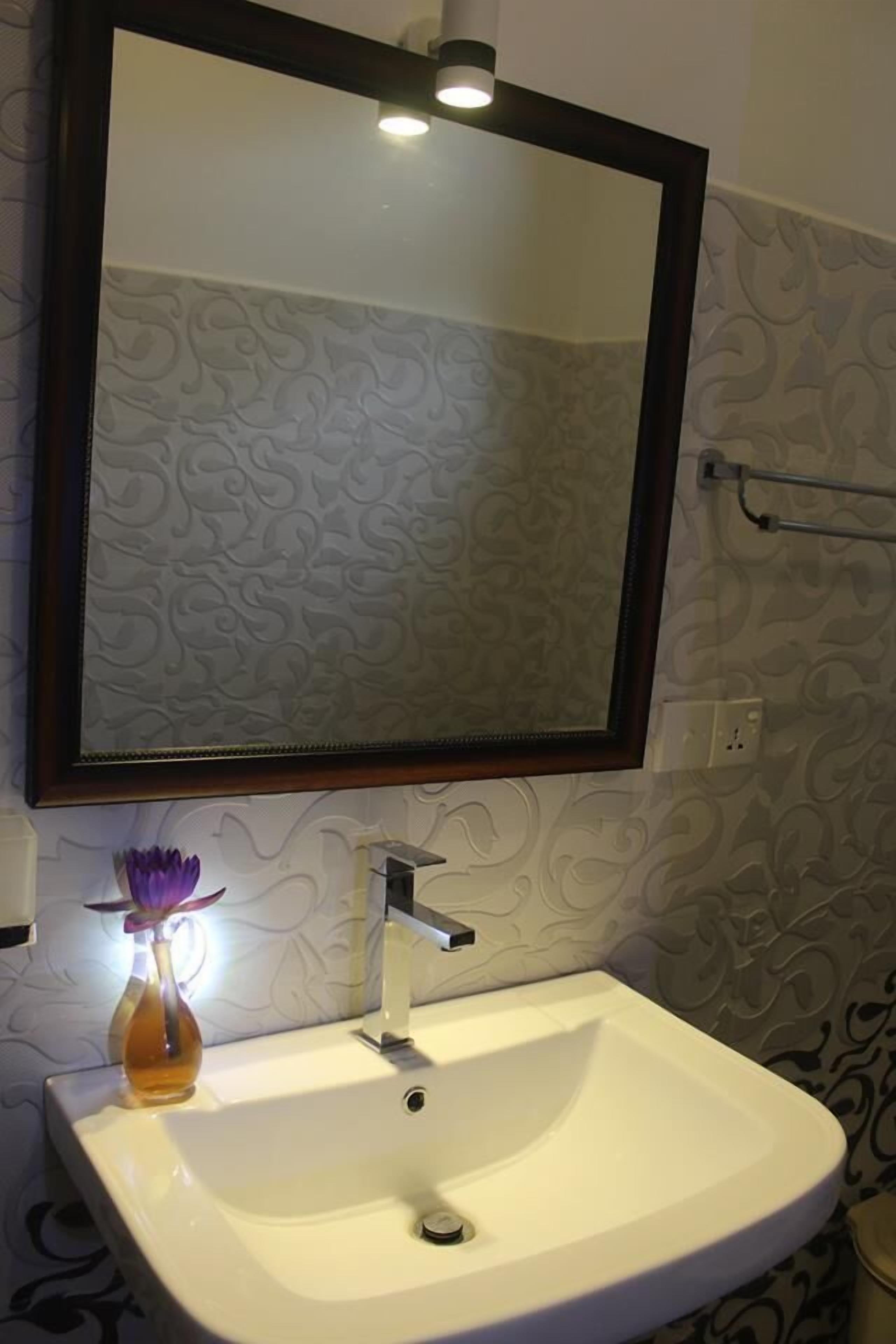 A bathroom with a white sink, a mirror, and a towel rack.