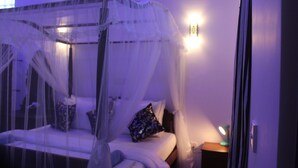 Une chambre à coucher avec un lit à baldaquin, des tables de chevet et une lampe fixée au mur.