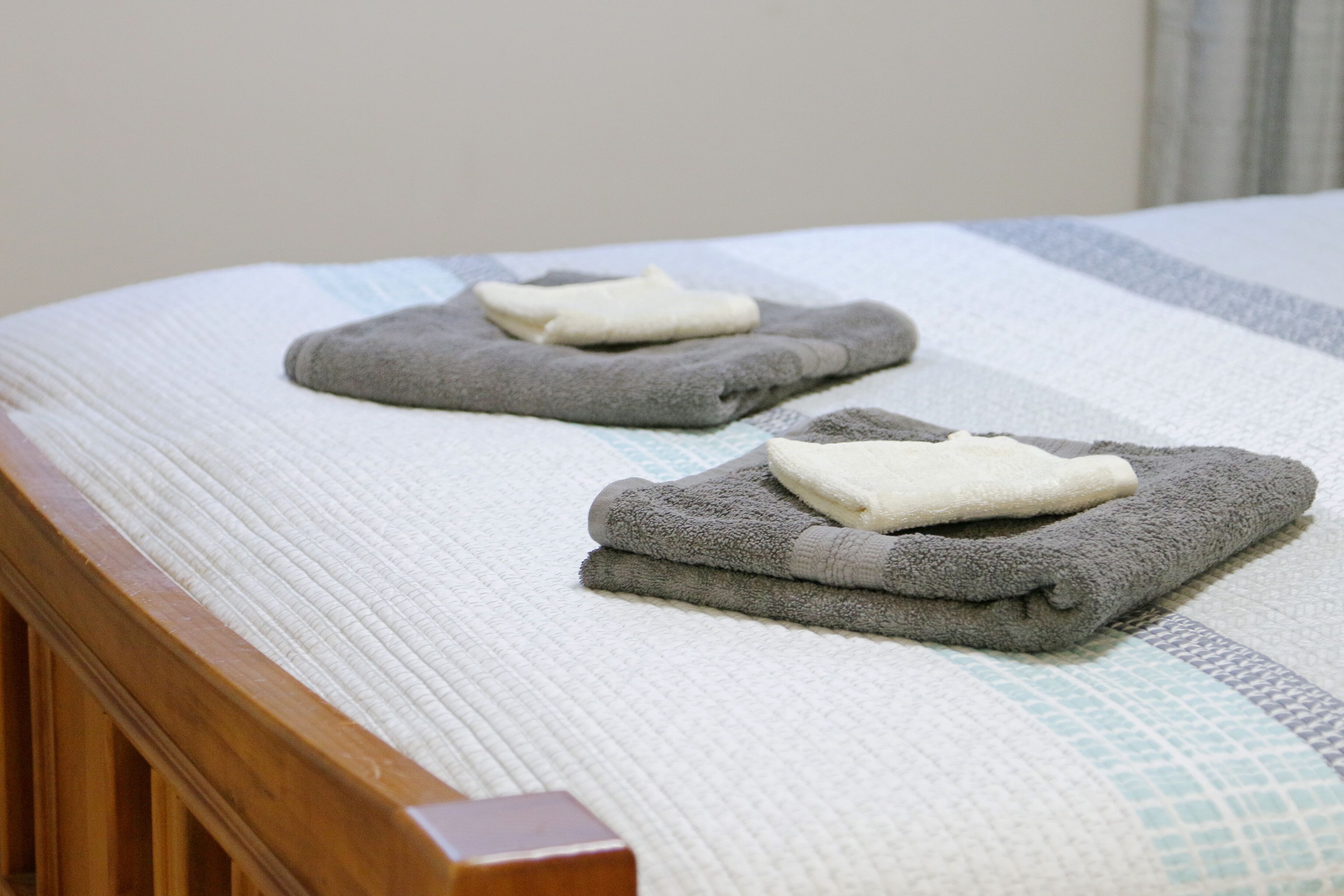 A neatly made bed with a striped bedspread and two folded towels placed on top.