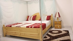 A four-poster canopy bed with a wooden frame and a white bedspread with red and white stripes. - Mama Rwanda Youth Hostel (Kigali)