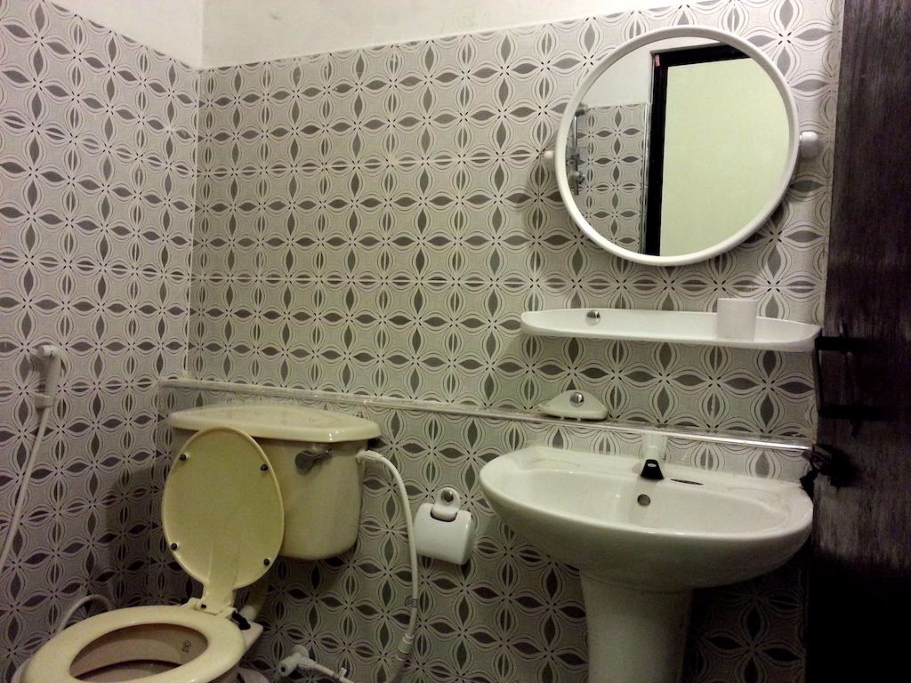A bathroom with a toilet, sink, and mirror.
