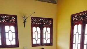 A bedroom with a large bed, two nightstands, a wall-mounted lamp, and decorative window grills. - Eliyana Guest House (Thalaramba)