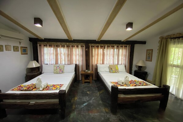 Une chambre avec deux lits simples, des têtes de lit en bois, des tables de chevet avec des lampes et des rideaux.