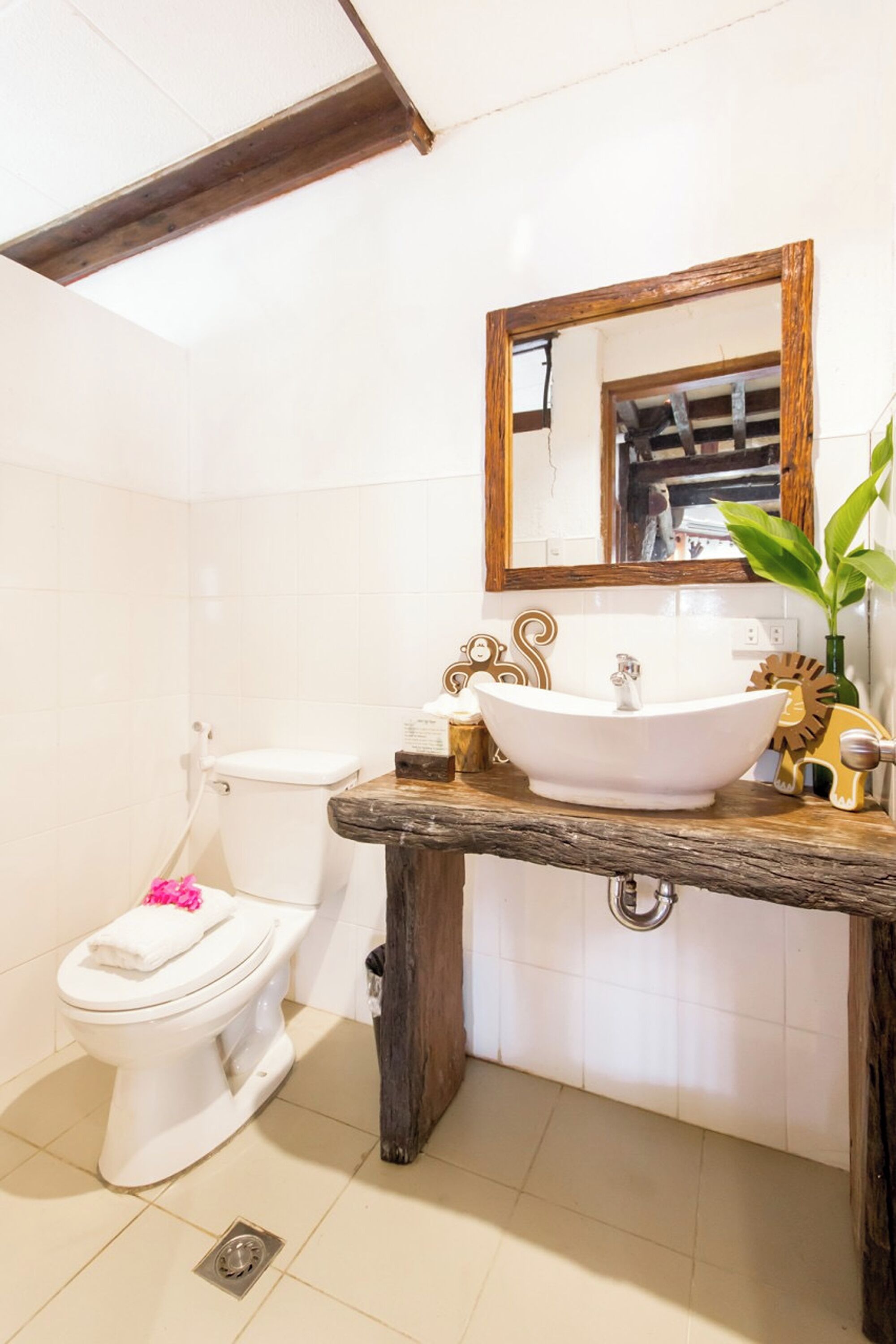 A bathroom with a white toilet, a wooden vanity with a white sink, and a mirror above the sink.