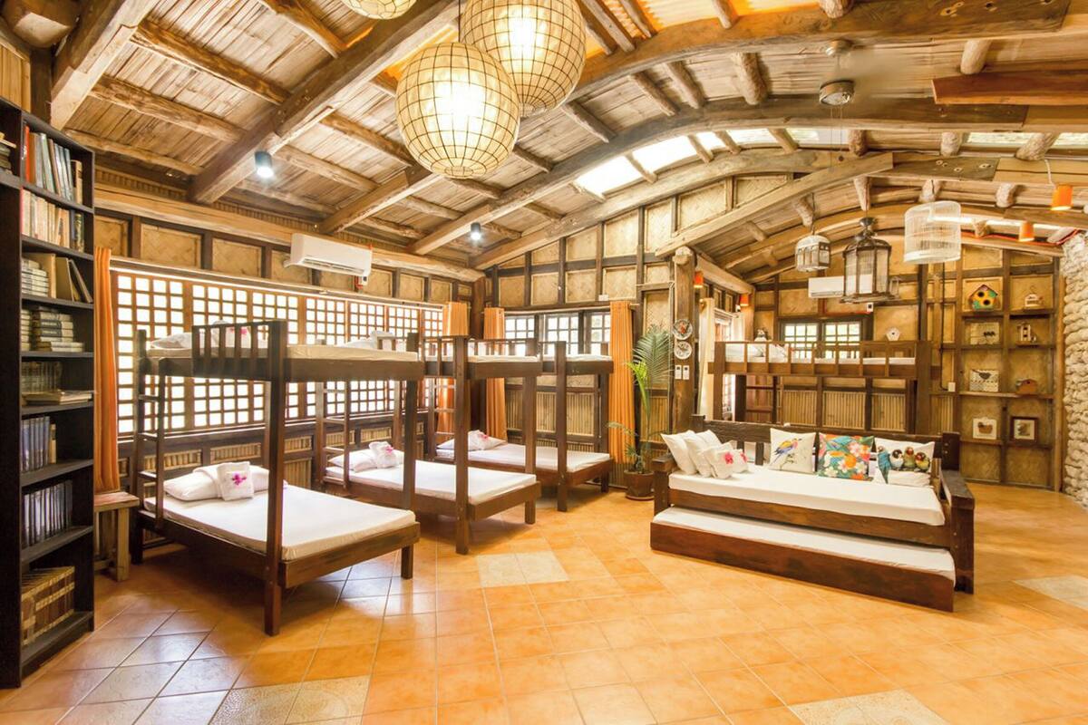 A rustic room with wooden bunk beds, a sofa, and a bookshelf.