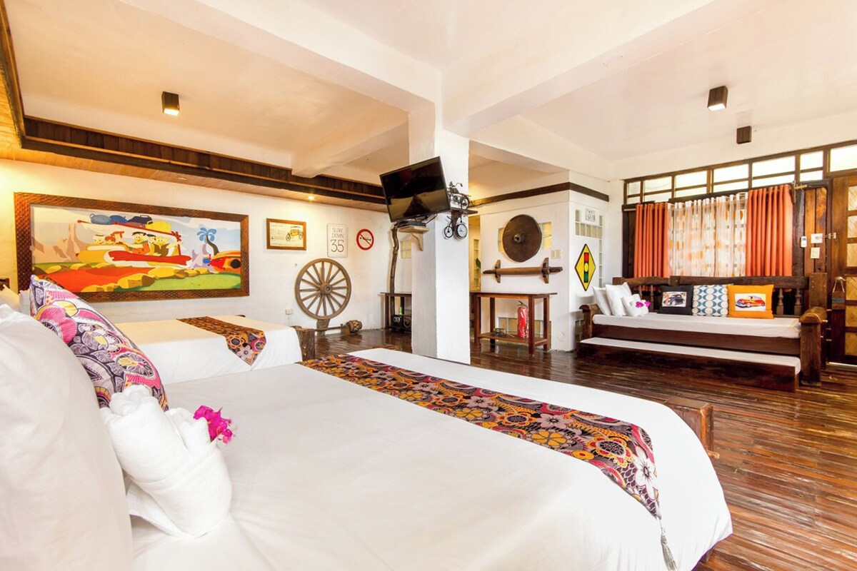 Una habitación de hotel amplia con una cama grande, un escritorio y una televisión.