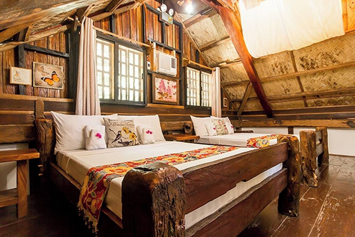 A rustic wooden room with a large bed, wooden headboard, and a wooden bench.