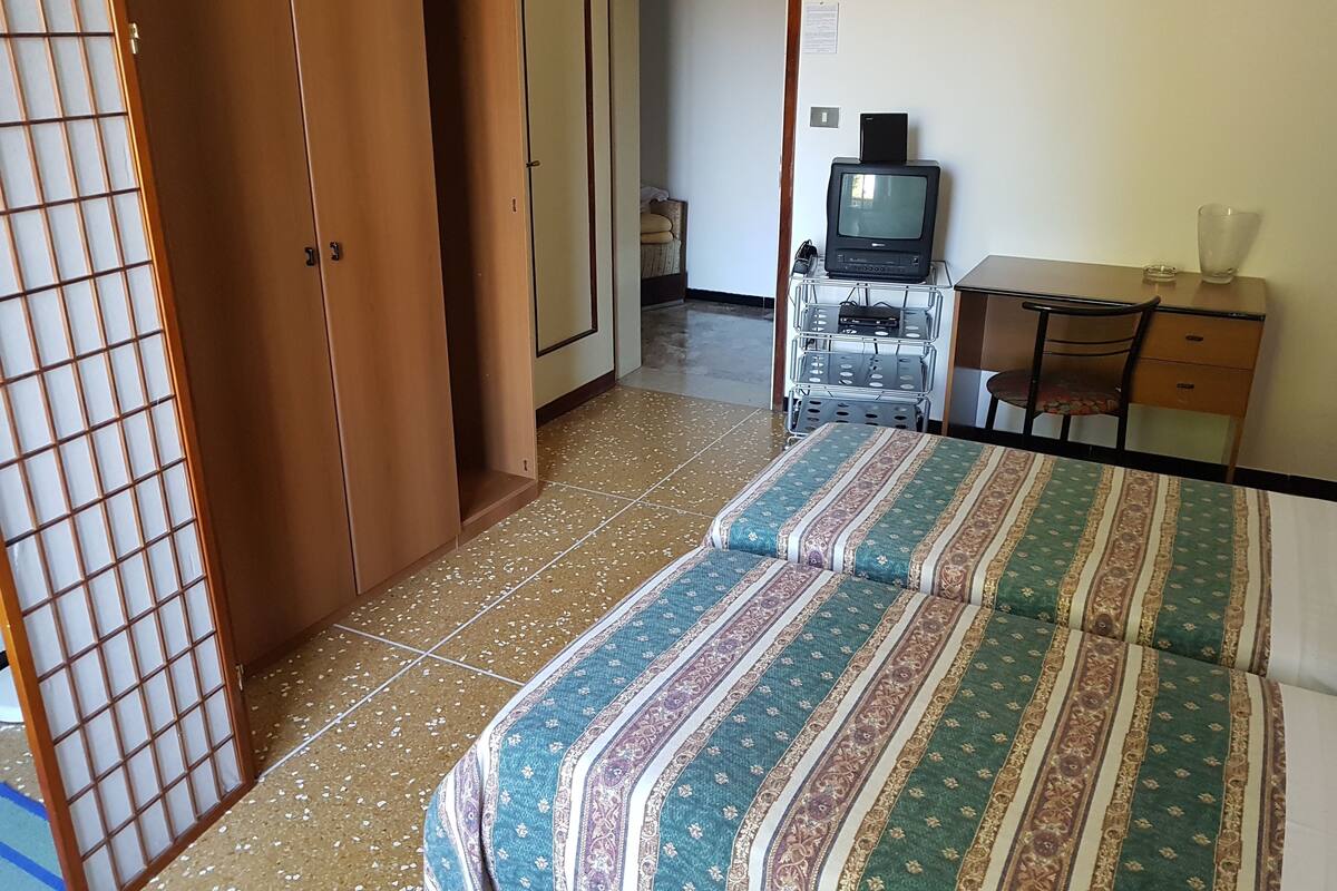 A hotel room with a bed, a desk, a television, and a wardrobe.
