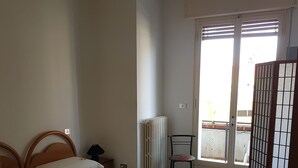 A room with two beds, a radiator, a chair, and a sliding glass door leading to an outdoor area. - Albergo Triana e Tyche (Sasso Marconi)