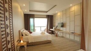 Una habitaci ón de hotel moderna con una cama grande, un escritorio, un televisor y vistas al exterior.