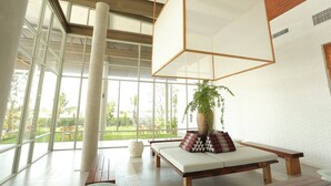 Un interior moderno con un ventanal grande, un banco de madera, una lámpara colgante y una planta en maceta.