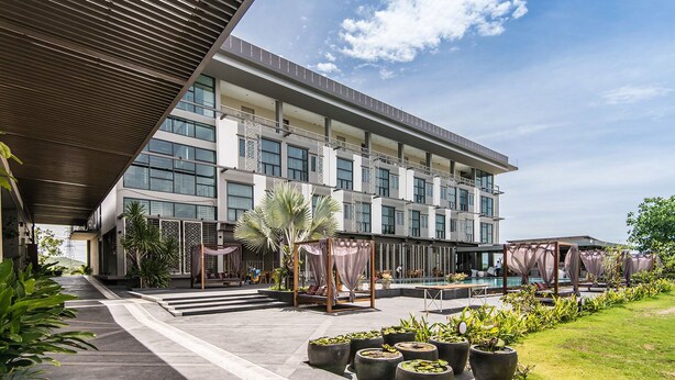 Un hotel moderno con una amplia fachada de vidrio, zona de estar al aire libre y piscina.
