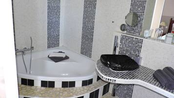 A bathroom with a bathtub, a sink, and a mirror.