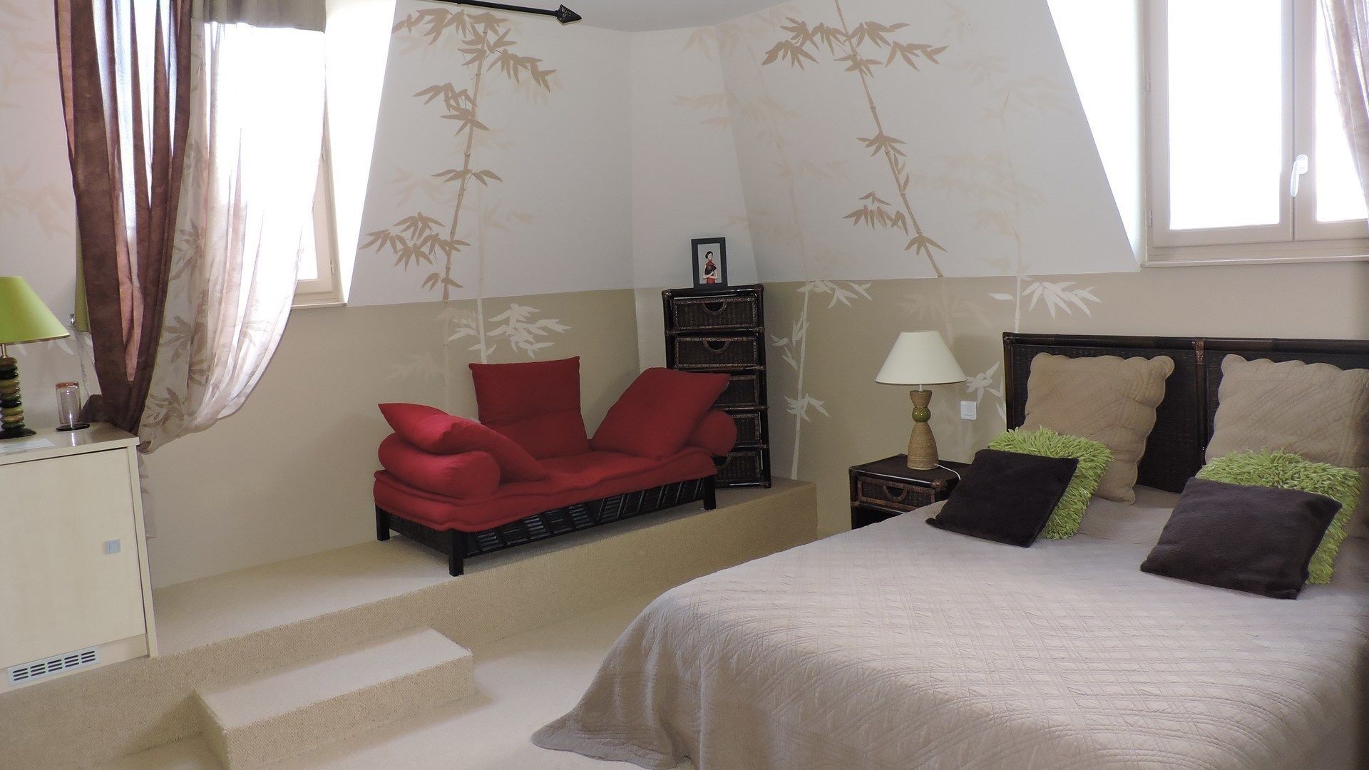 Un dormitorio con cama, una silla roja, una mesita de noche, una lámpara y una pared con diseño de bambú.