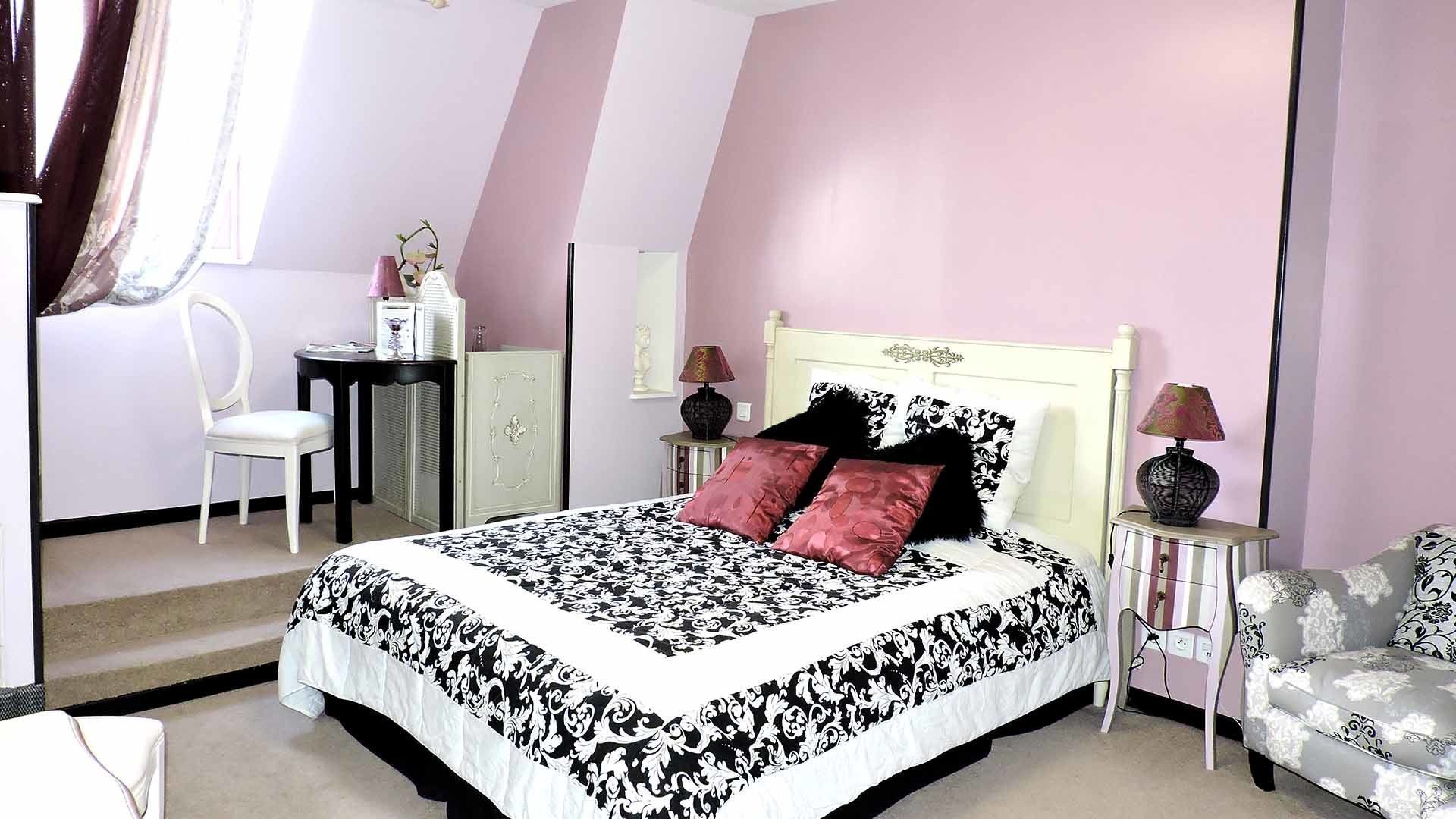 Een slaapkamer met een bed, stoel, bureau en lamp.