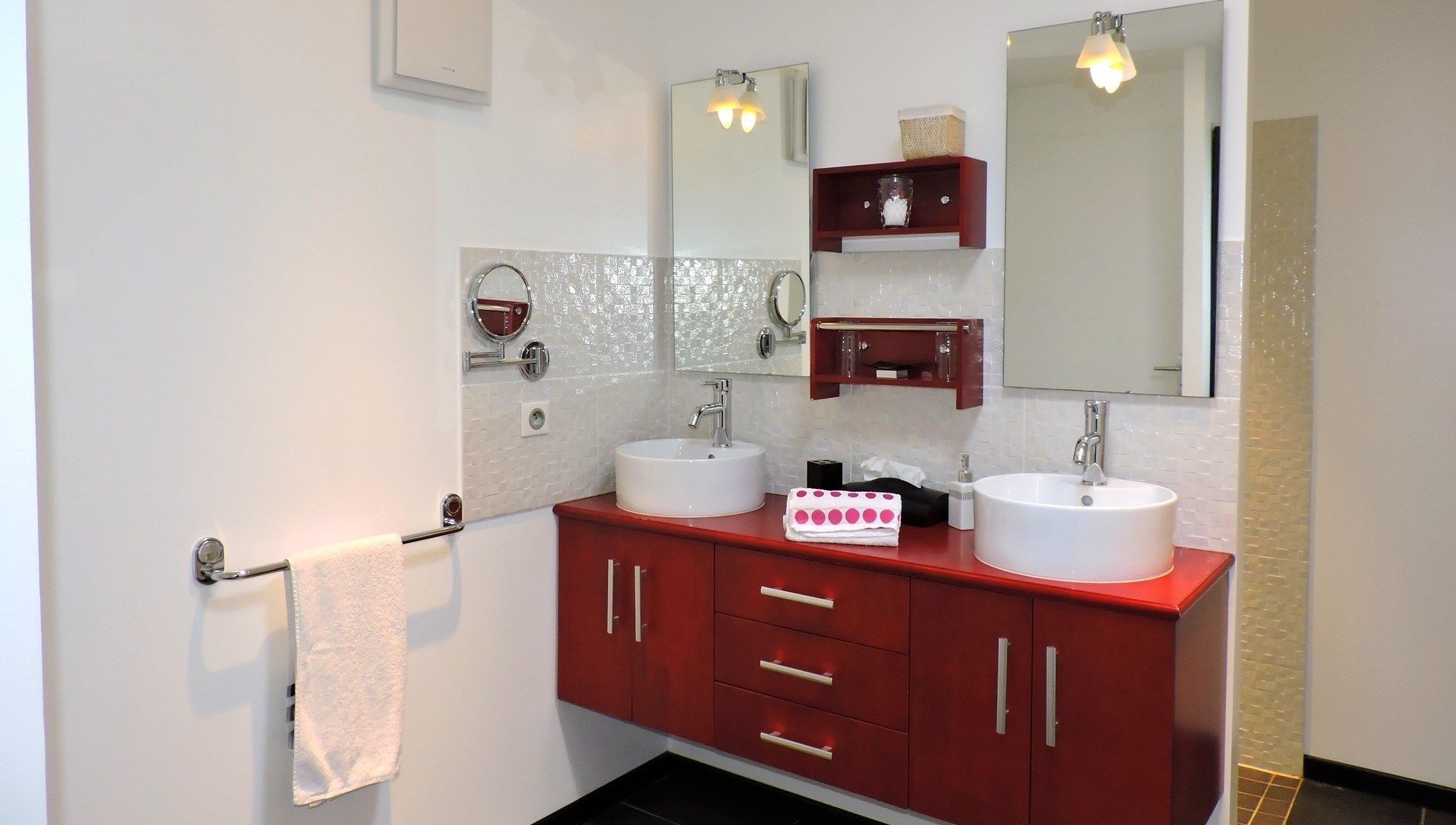 A modern bathroom with two sinks, a mirror, and a towel rack.