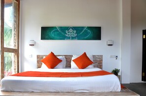 A hotel room with a large bed, two orange pillows, a white bedspread, and a green abstract painting on the wall. - Sithu Villa Hikkaduwa (Hikkaduwa)