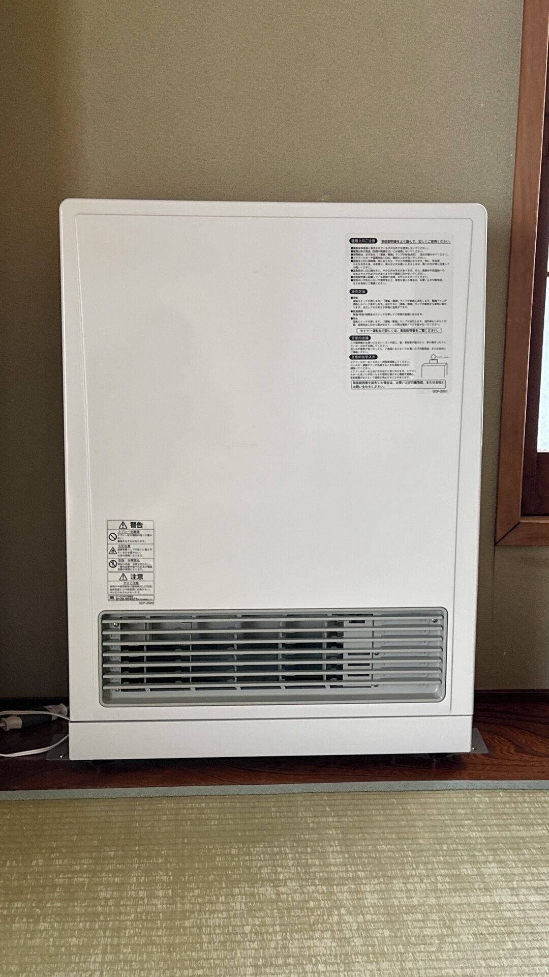 A white portable heater with a vent and a label on the back.
