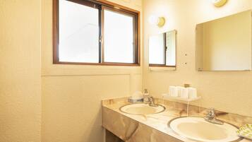 A bathroom with two sinks, a window, and a mirror.
