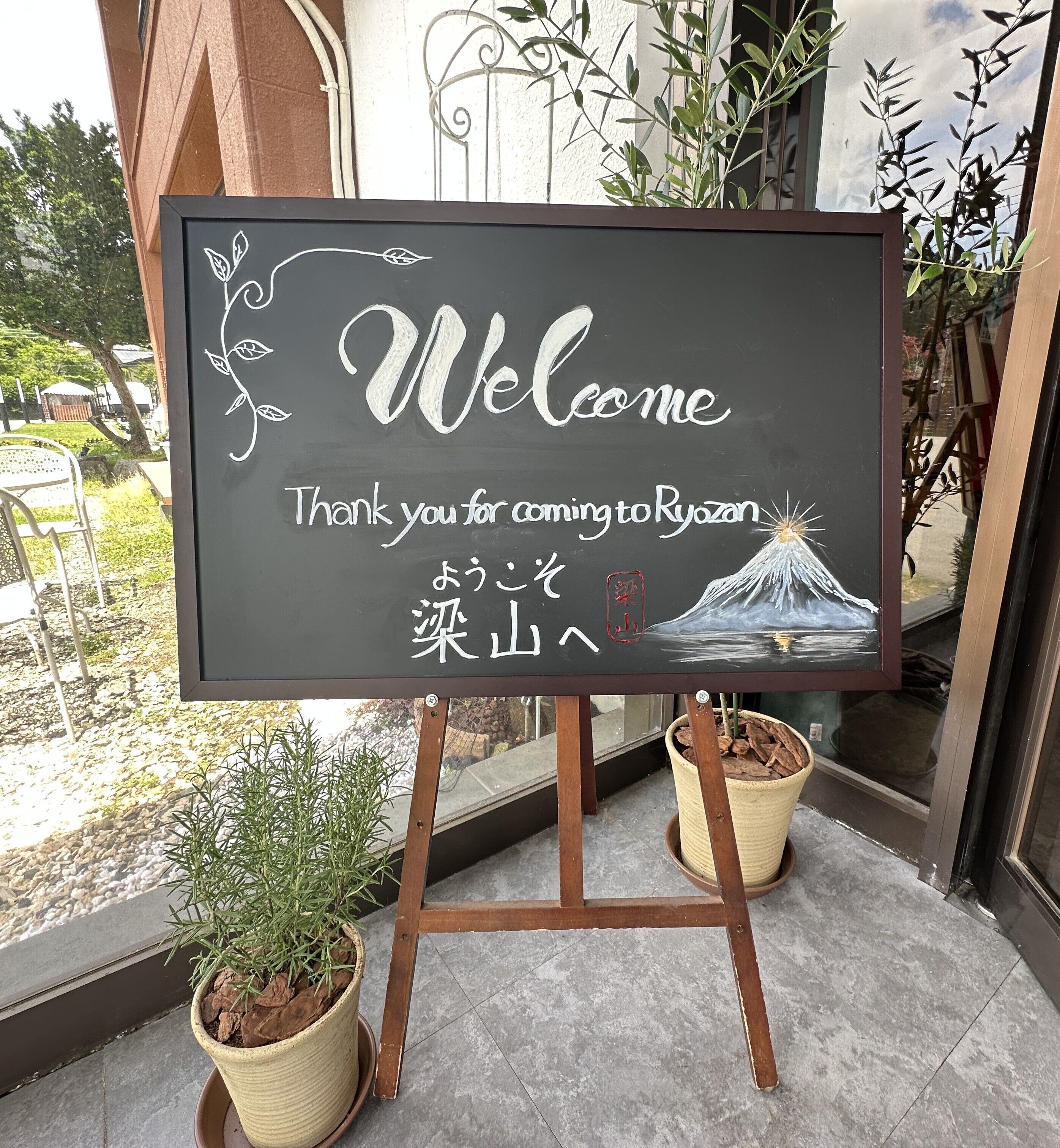 A welcome sign with 'Welcome' and 'Thank you for coming to Ryazan' written on it, along with a mountain illustration.