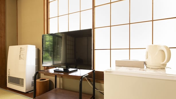 A room with a wooden desk, a television, a white refrigerator, and a window with a grid pattern. - Yamanakako Ryokan RYOZAN (Yamanakako)
