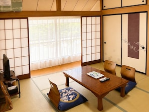 Una habitación japonesa tradicional con suelo de tatami, una mesa de madera baja y puertas correderas shoji.