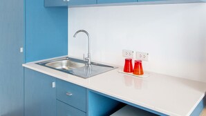 A kitchen with a stainless steel sink, blue cabinets, and a white countertop. - 128 Room And Massage (Bangkok)