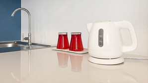 A kitchen with a white kettle, a red mug, and a faucet. - 128 Room And Massage (Bangkok)