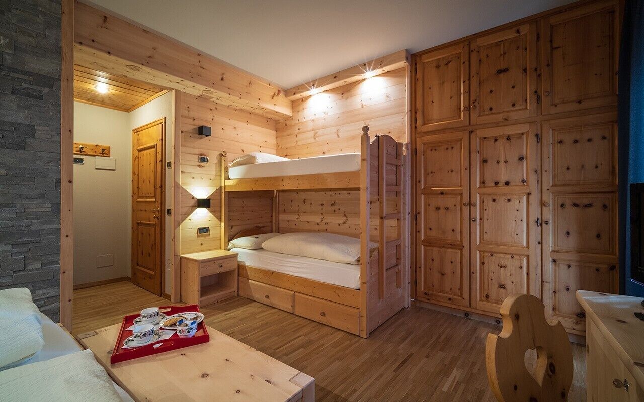 A wooden cabin room with bunk beds, a small table with a tray of food, and a wooden cabinet.