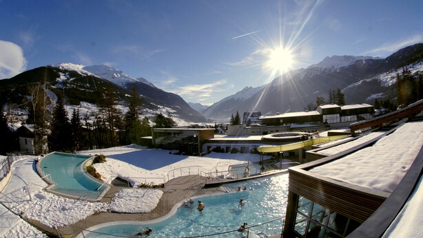 Zona de piscina con vistas a montañas nevadas y cielo despejado.