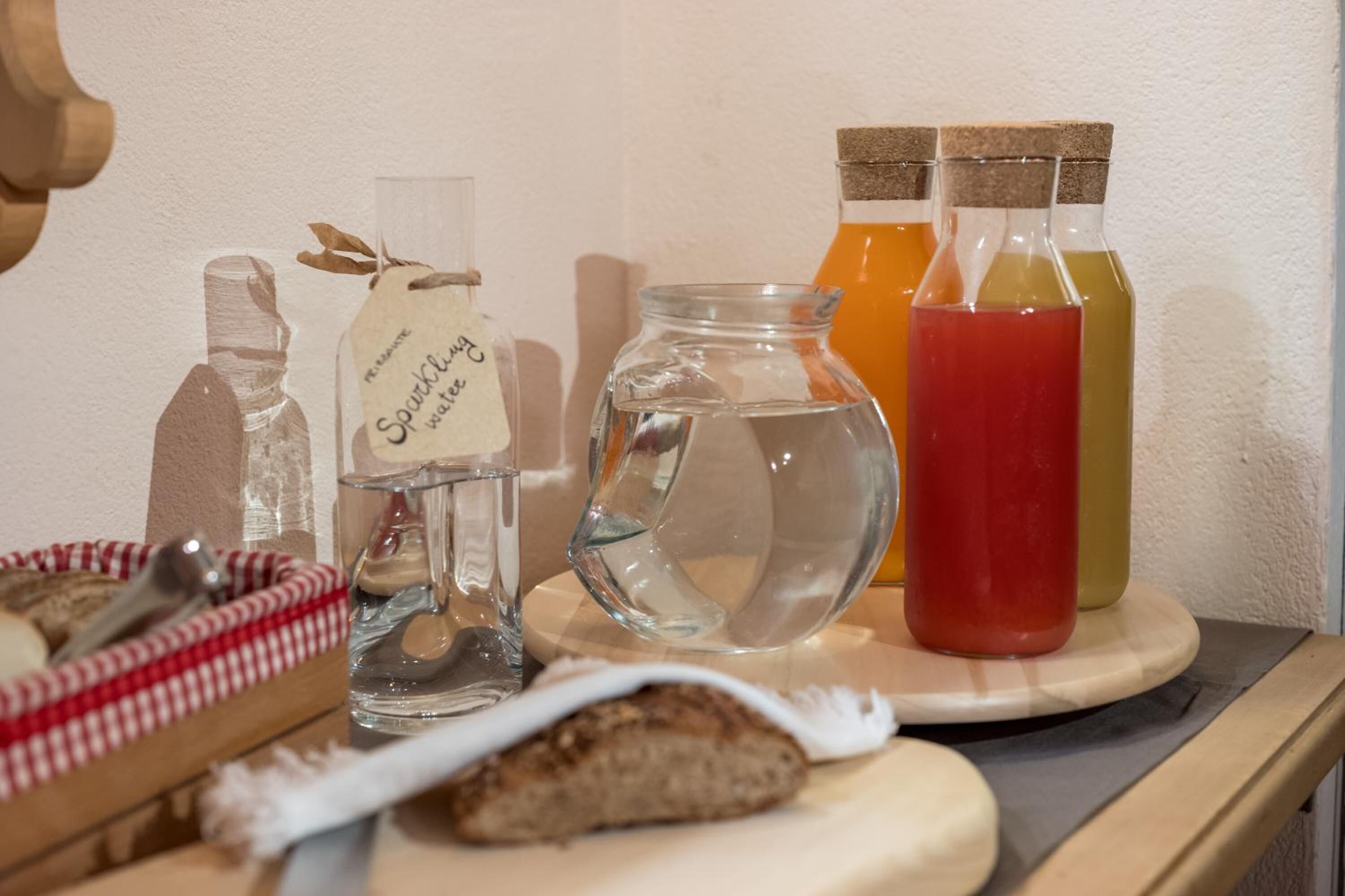 Un tavolo con un barattolo di vetro, una bottiglia con l'etichetta “Sparkling Water” e due bottiglie di liquidi colorati.