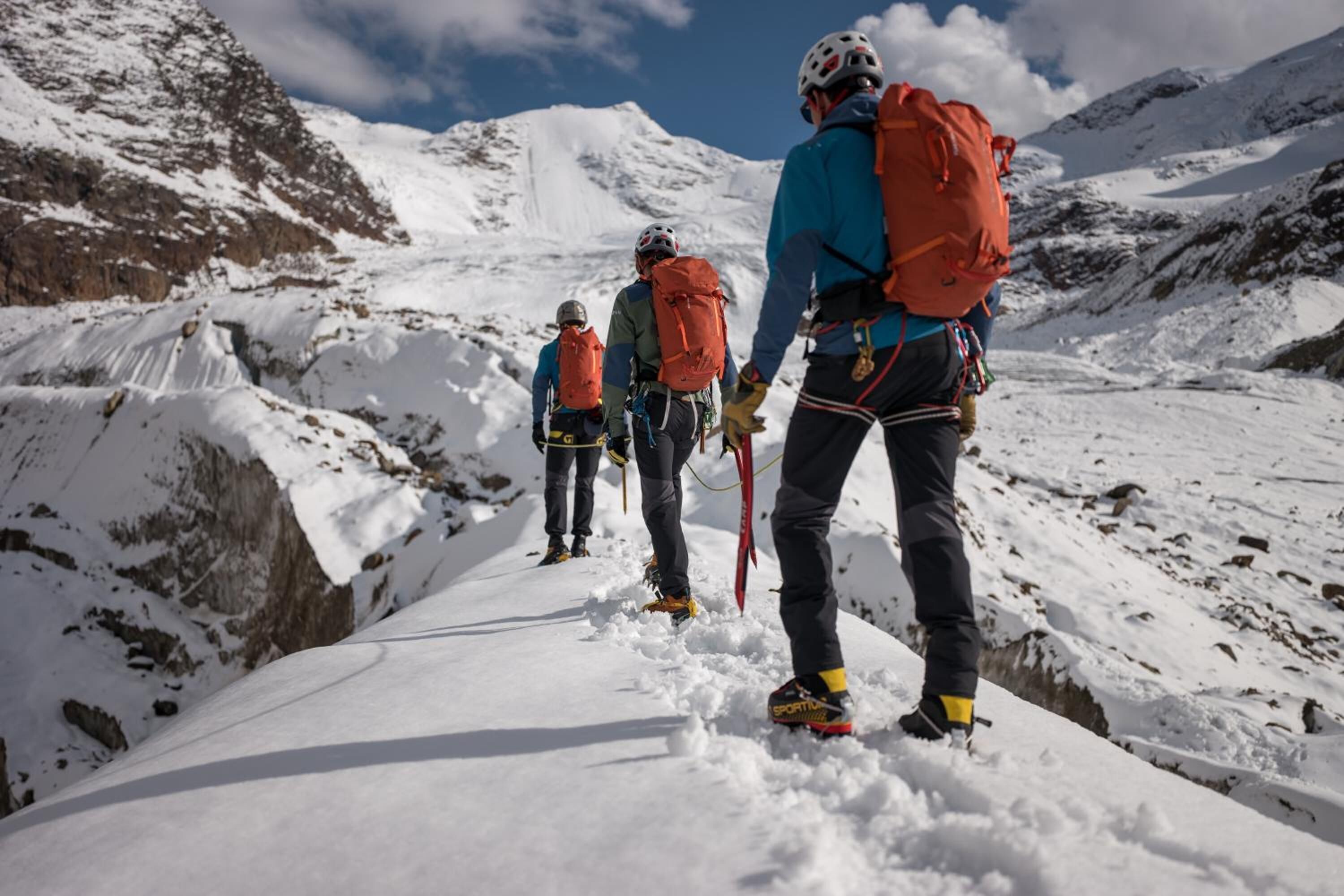 Un grupo de alpinistas en un sendero nevado de montaña.