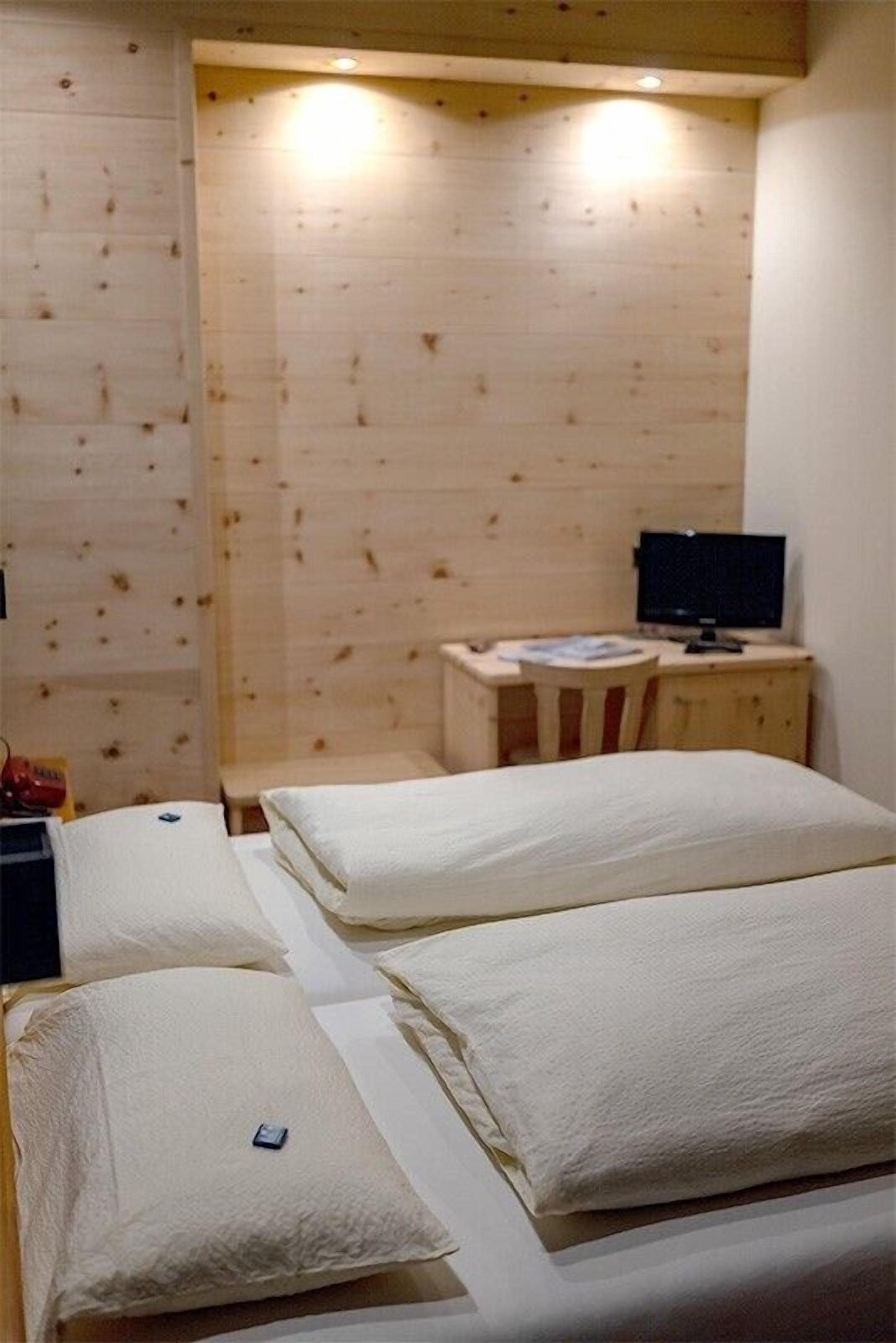 A room with two beds, a desk with a computer, and a small cabinet.