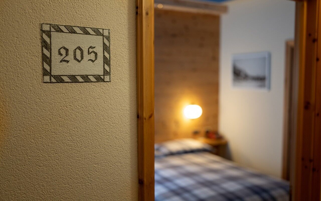 Una habitación con una cama, una lámpara de pared y una puerta con el número 205.
