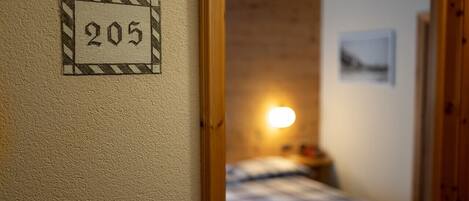 Una habitación con una cama, una lámpara de pared y una puerta con el número 205.