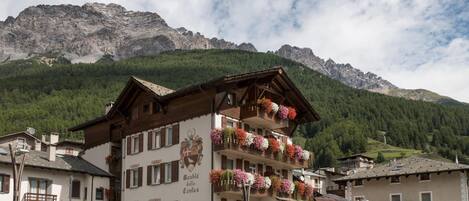 Un edificio de varios pisos con balcones decorados con flores, con montañas al fondo.