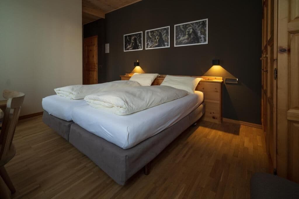 Un letto matrimoniale con biancheria da letto bianca, due comodini con lampade e tre quadri appesi al muro.