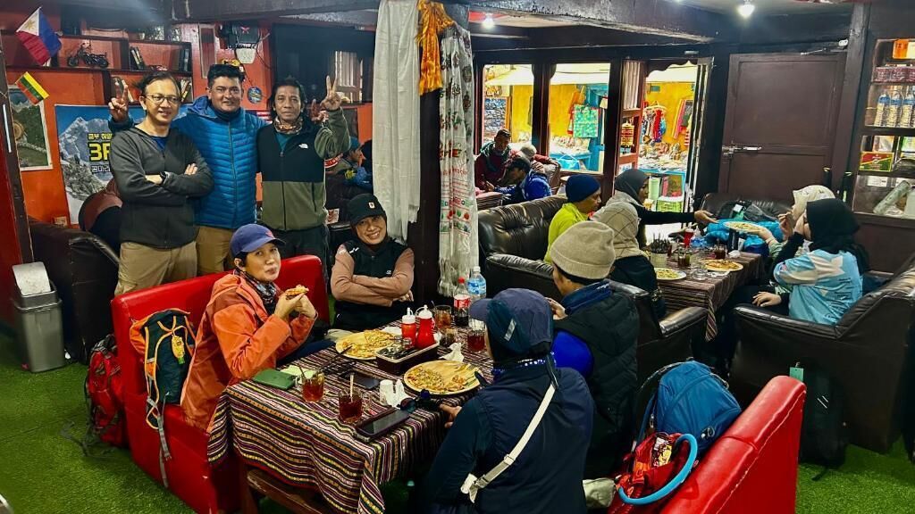 Comedor con mesas y sillas, personas sentadas comiendo y un mostrador con artículos a la venta.