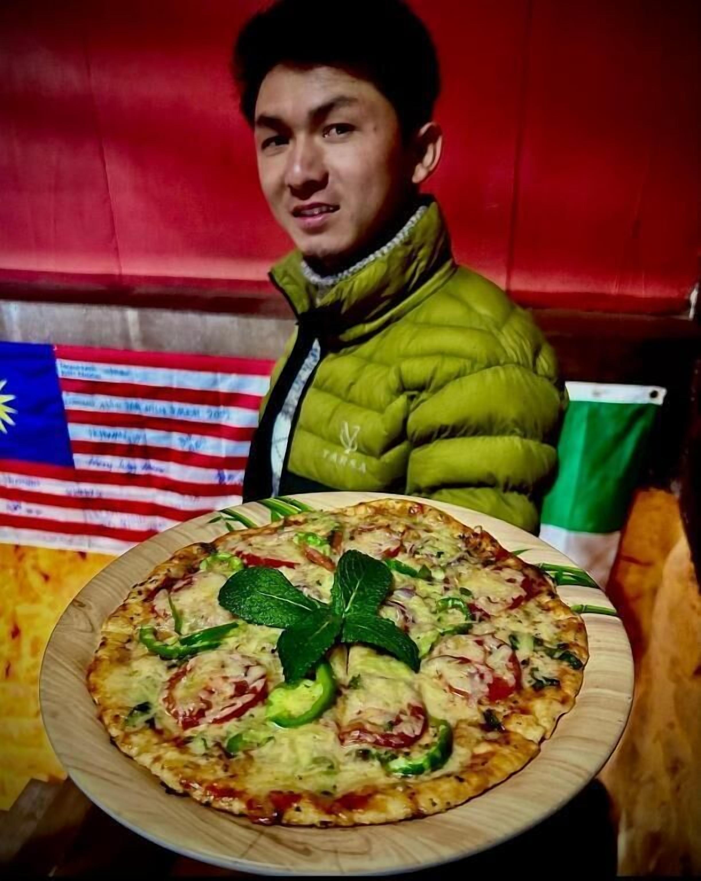 Une personne est assise à une table devant une pizza.