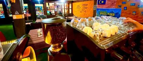 Zona de bar con una máquina de café, un tarro grande de granos y una pizarra de menú.
